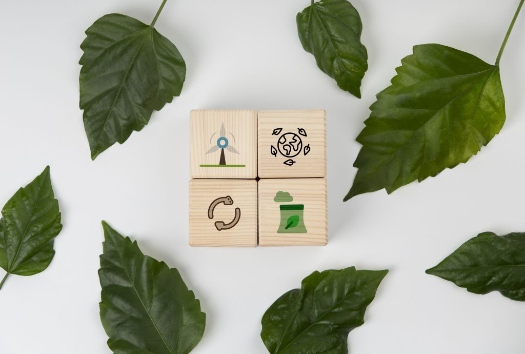 Wooden blocks with eco-friendly symbols—wind energy, recycling, sustainable production, and earth conservation—surrounded by green leaves, representing the core principles of ESG investment funds.