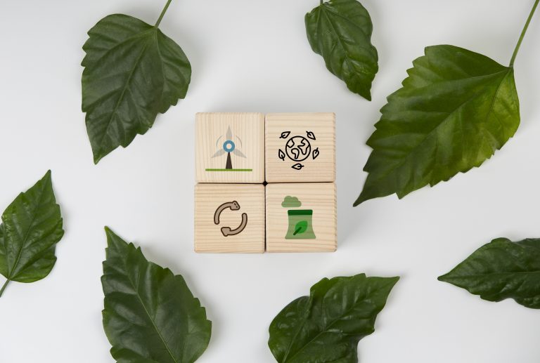 Wooden blocks with eco-friendly symbols—wind energy, recycling, sustainable production, and earth conservation—surrounded by green leaves, representing the core principles of ESG investment funds.