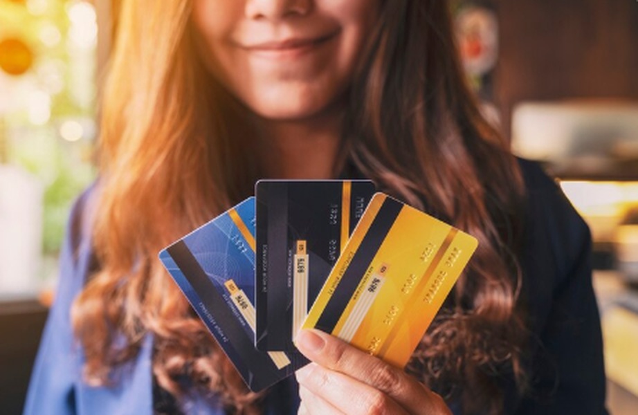 Smiling woman holding several credit cards in her hand, representing the importance of choosing the best fraud protection cards for secure spending in 2025.