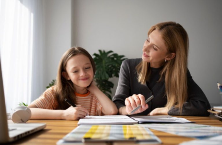 A mother guiding her daughter through homework at a desk, illustrating early financial planning education in a supportive home environment.