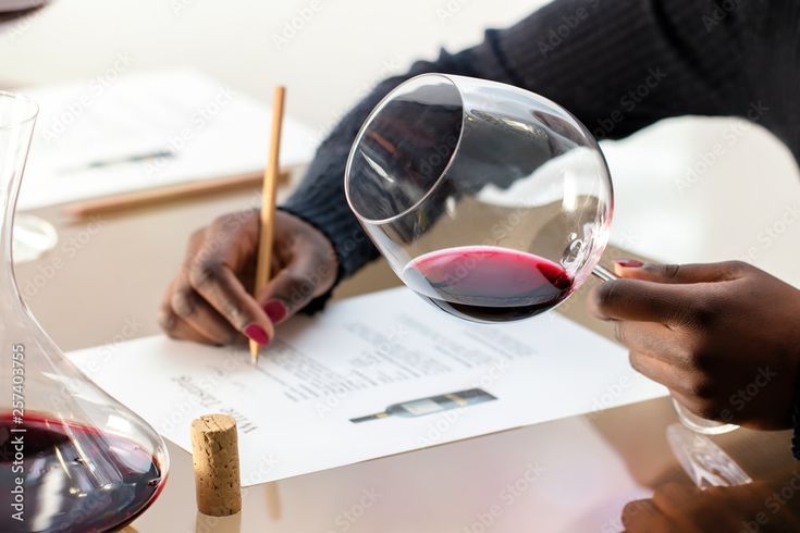 A person holding a glass of red wine while taking notes during a tasting session, symbolizing how fine wine can be part of alternative investments in the U.S.