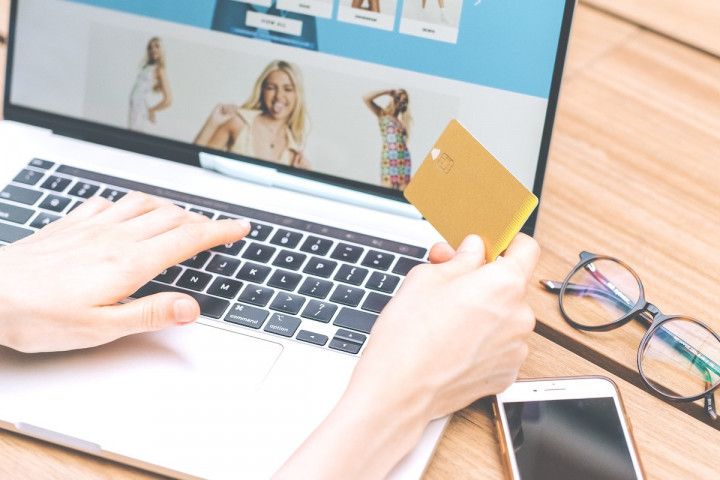A person shopping online with a laptop and holding a gold credit card, showcasing the benefits of using the best cashback credit cards with no annual fee for online purchases.