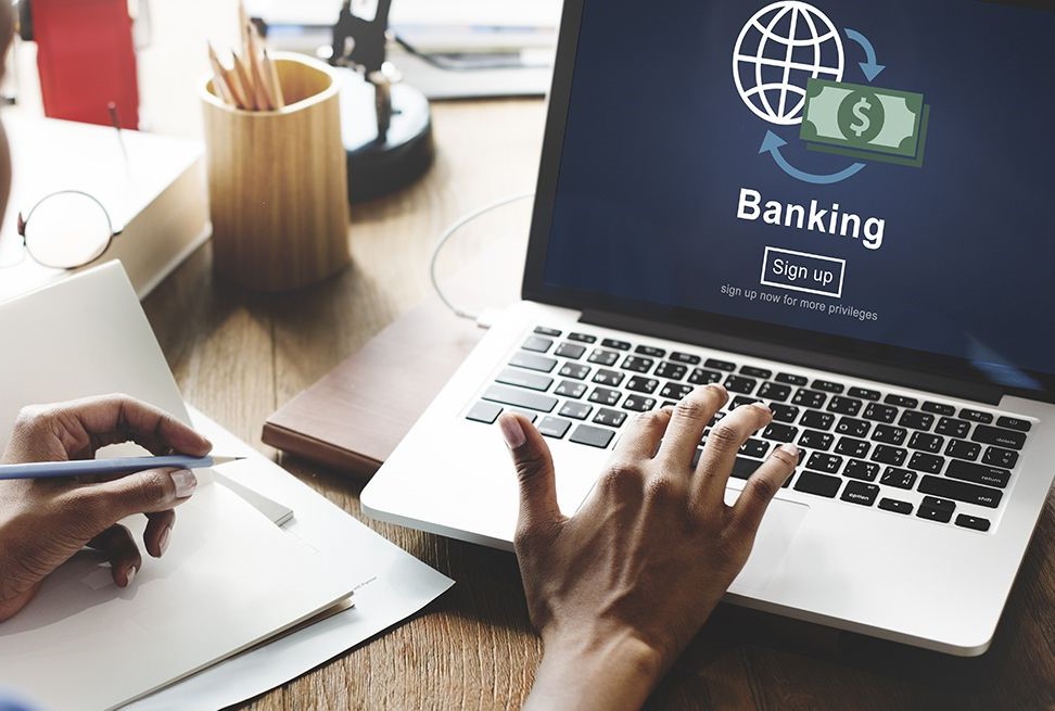 A person uses a laptop showing an online banking sign-up screen while taking notes, symbolizing accessibility, simplicity, and the convenience of the best online banks for beginners.