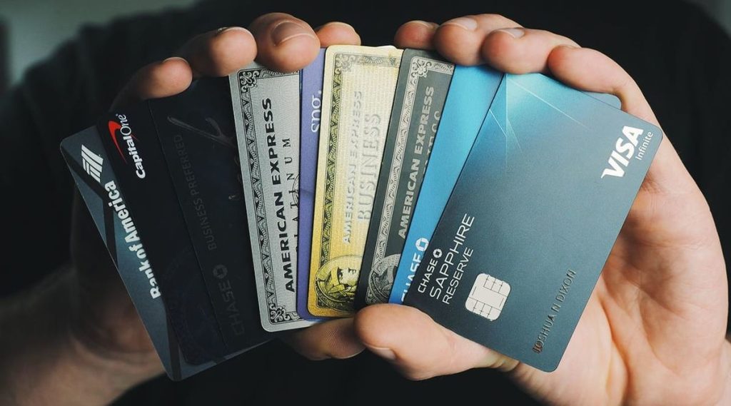 Close-up of a hand holding several premium credit cards, including Chase, American Express, and Capital One — showcasing some of the best travel credit cards for earning miles, rewards, and luxury travel perks.