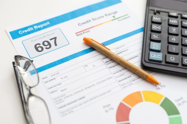 Credit report showing a score of 697 alongside a calculator, glasses, and a pen, illustrating the process of reviewing finances and learning how to dispute errors on your credit report.