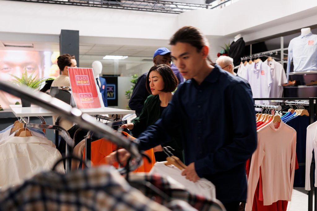 Shoppers browsing clothes during a Black Friday sale, illustrating how to control impulse spending in retail environments with promotional triggers.